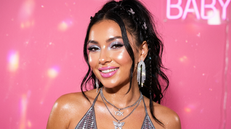 Model with glowing highlighted cheekbones Y2K makeup look, strobing highlight, bubblegum pink background