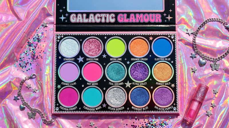 Grand 15-pan eyeshadow palette flat lay on bubblegum pink holographic foil with rhinestone star charms - Y2K maximalist beauty