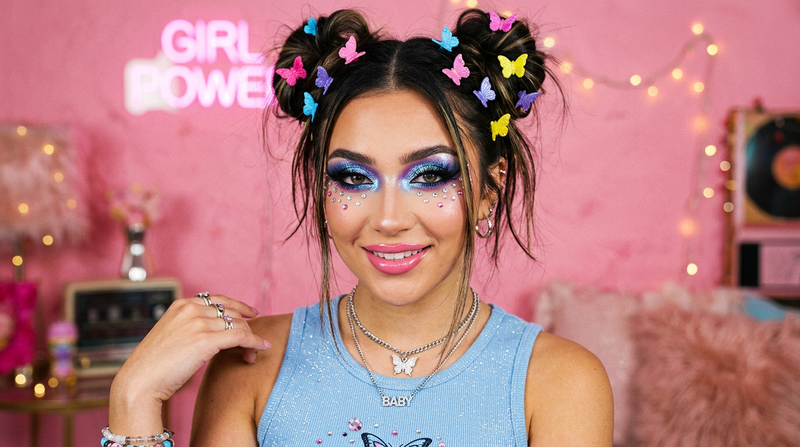 Model wearing bold Y2K eye makeup with cosmic metallic eyeshadow and rhinestone gems